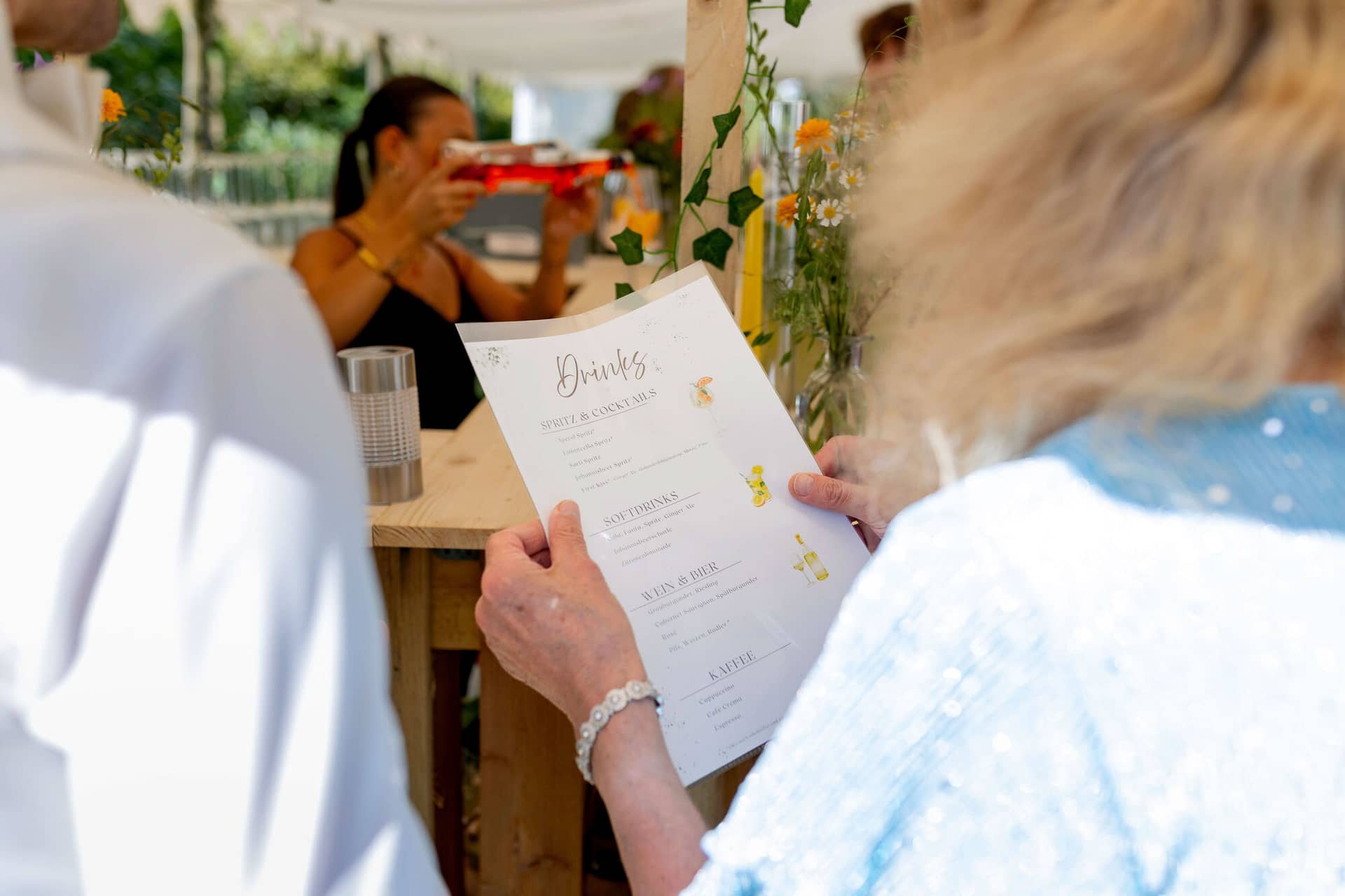 20250830 15 43 28 4K8A1737.Bt6wKMyC Gästin liest die Getränkekarte an der Hochzeitsbar