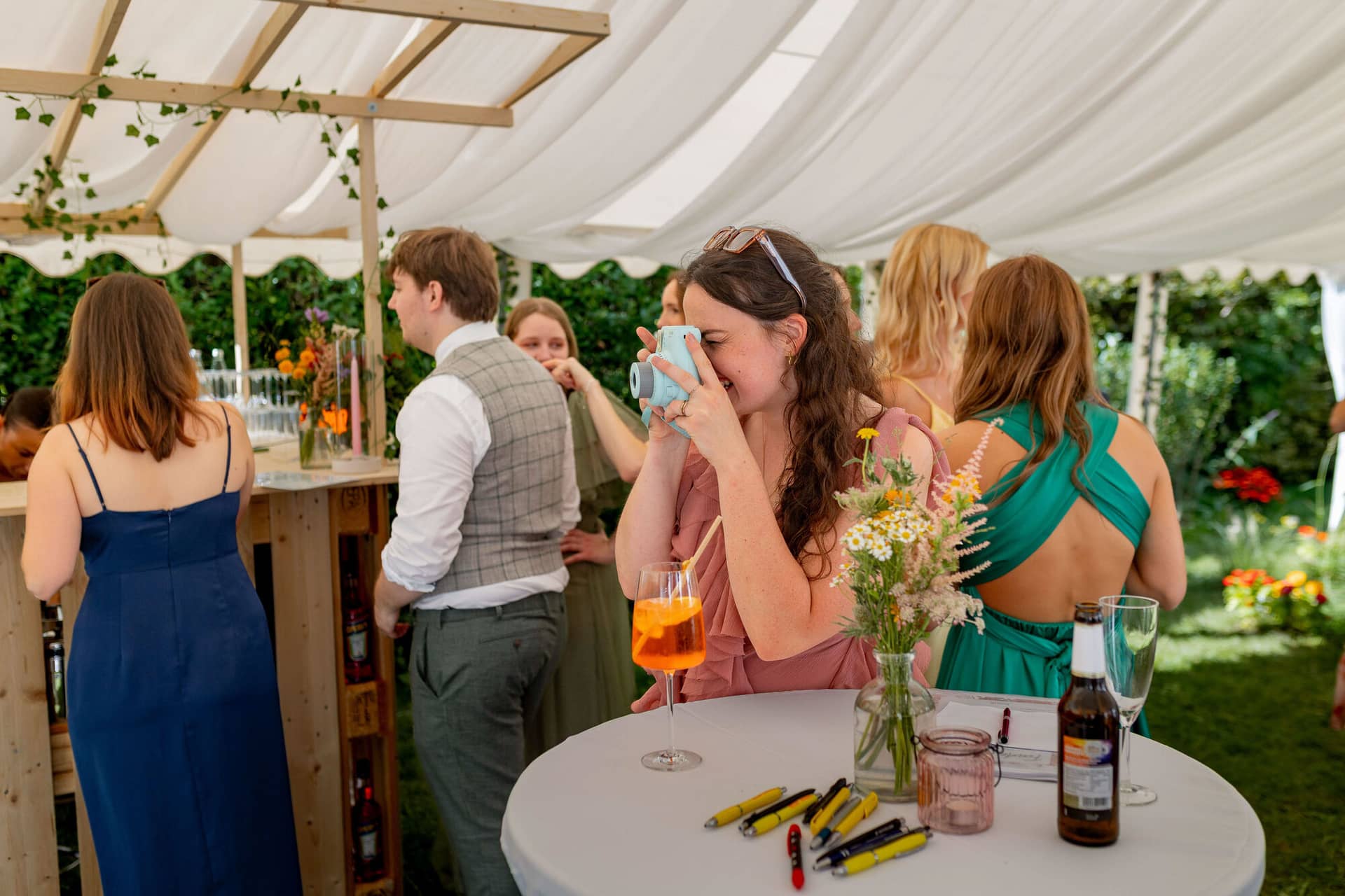 20250830 15 49 45 4K8A1849.BrbvHX5X Gästin fotografiert lachend mit Instax-Kamera unter dem Zelt