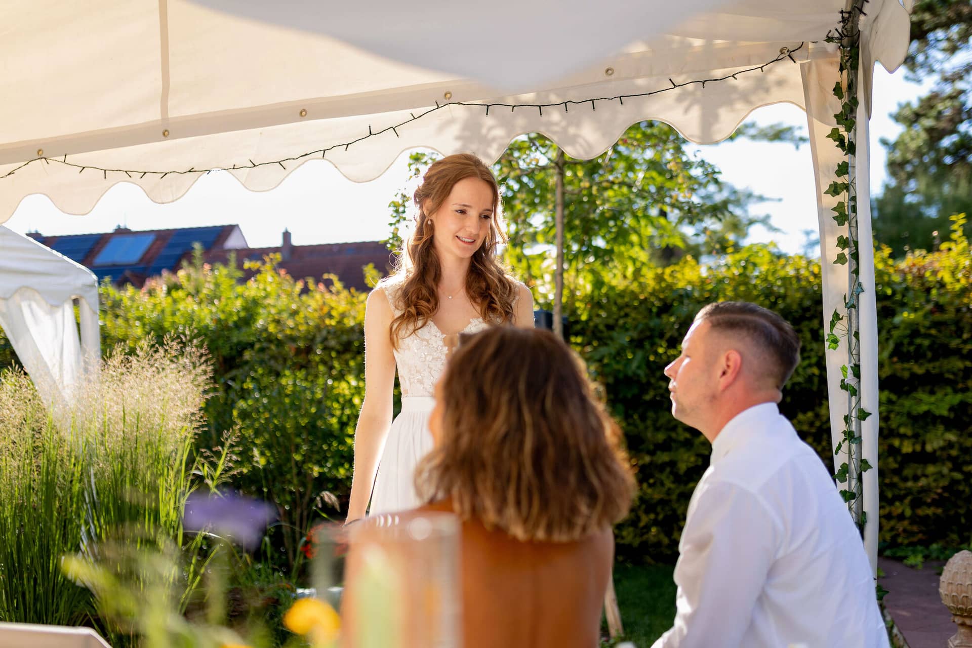 20250830 17 54 57 4K8A3187.T1iB2GQj Braut steht lächelnd im Abendlicht unter dem Gartenzelt