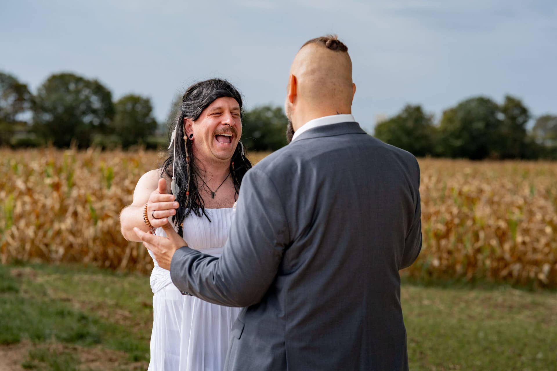 20250913 11 25 05 DSC04483.CETnVAS2 Freund im weißen Kleid und Bräutigam lachen herzlich beim First-Look-Streich