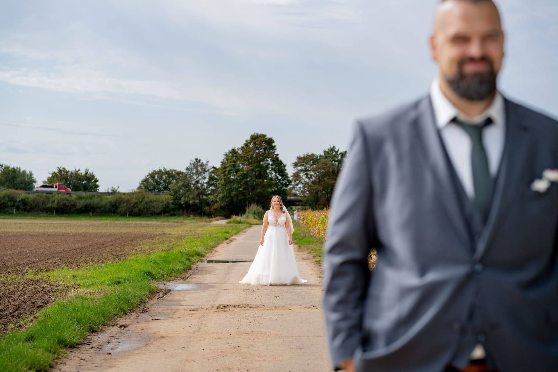 20250913 11 29 00 DSC04527.2HSX7DAs Braut im Brautkleid nähert sich dem wartenden Bräutigam auf dem Feldweg