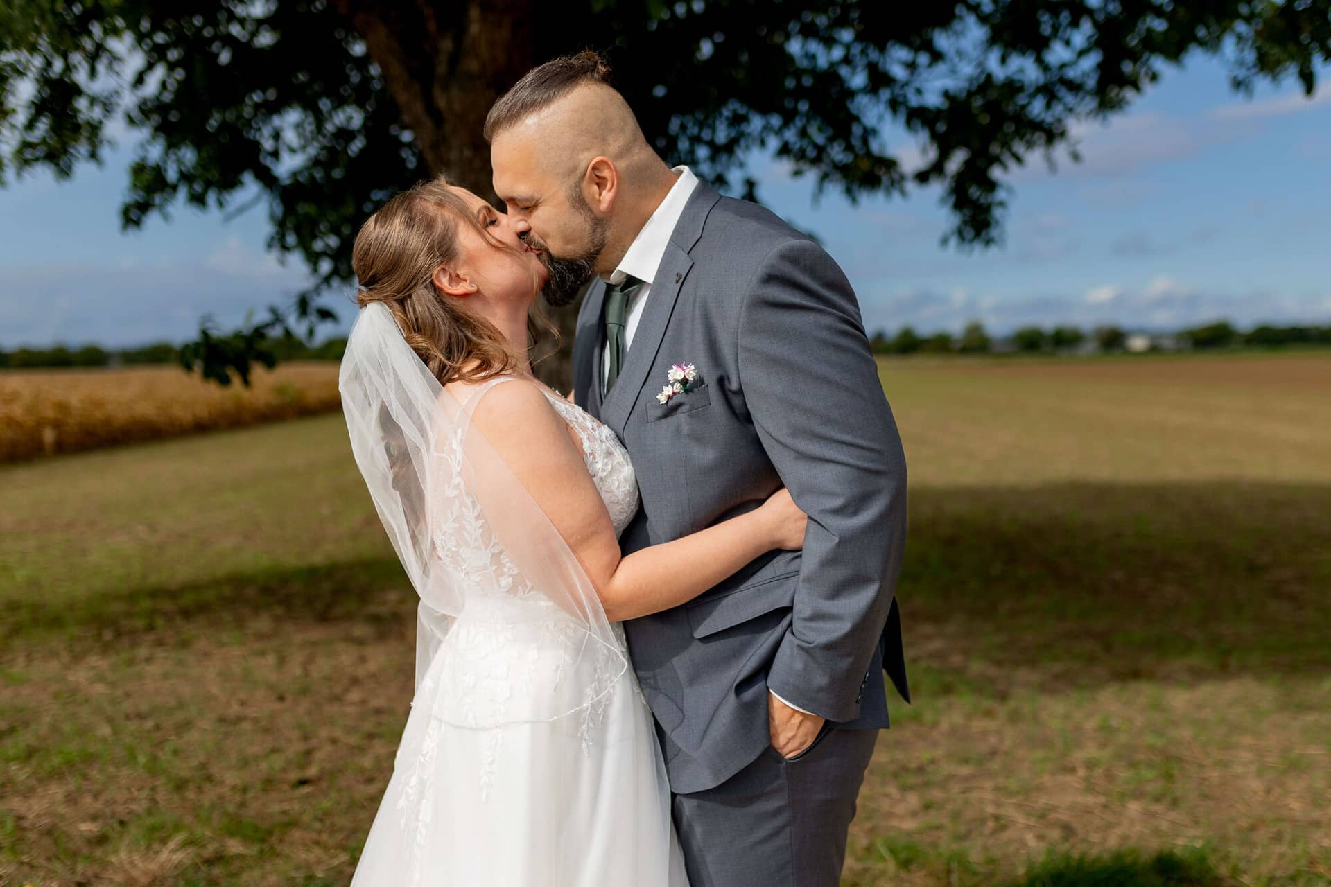 20250913 11 29 56 4K8A4259.Bo8rb2fk Brautpaar küsst sich unter einem Baum auf der Wiese