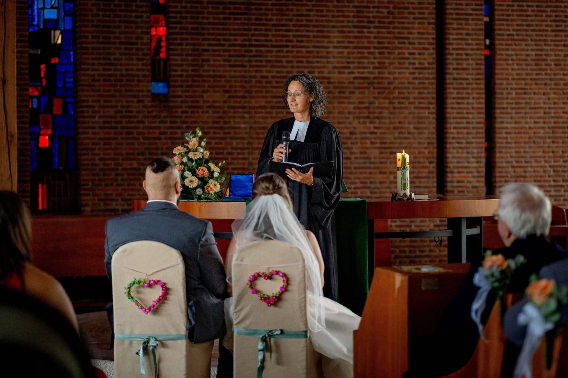 20250913 12 26 52 DSC04910.DkrmtrP Pfarrerin spricht vor dem sitzenden Brautpaar in der Christuskirche