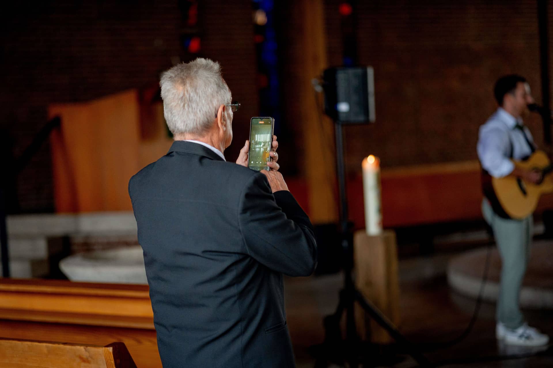 20250913 12 30 37 DSC04990.1kLoFLry Gast filmt mit dem Handy während Gitarrist im Hintergrund spielt