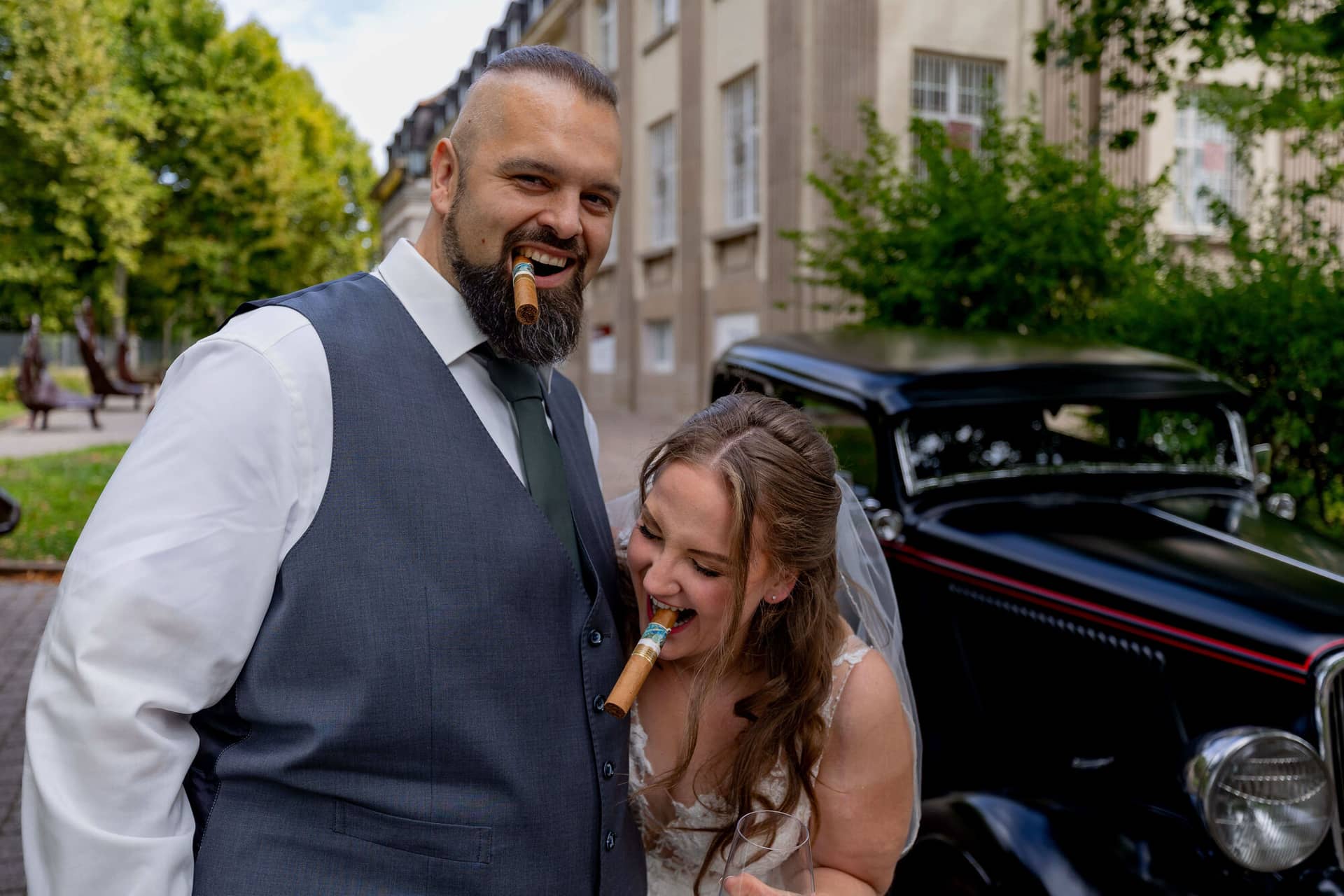 20250913 14 10 52 4K8A5982.DnDFd4pE Brautpaar posiert lachend mit Zigarren vor dem Oldtimer