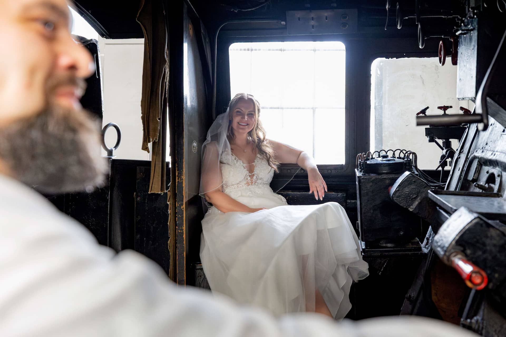 20250913 15 21 40 4K8A6627.D1atWJvD Braut sitzt lächelnd im Führerstand der Dampflok im Gegenlicht