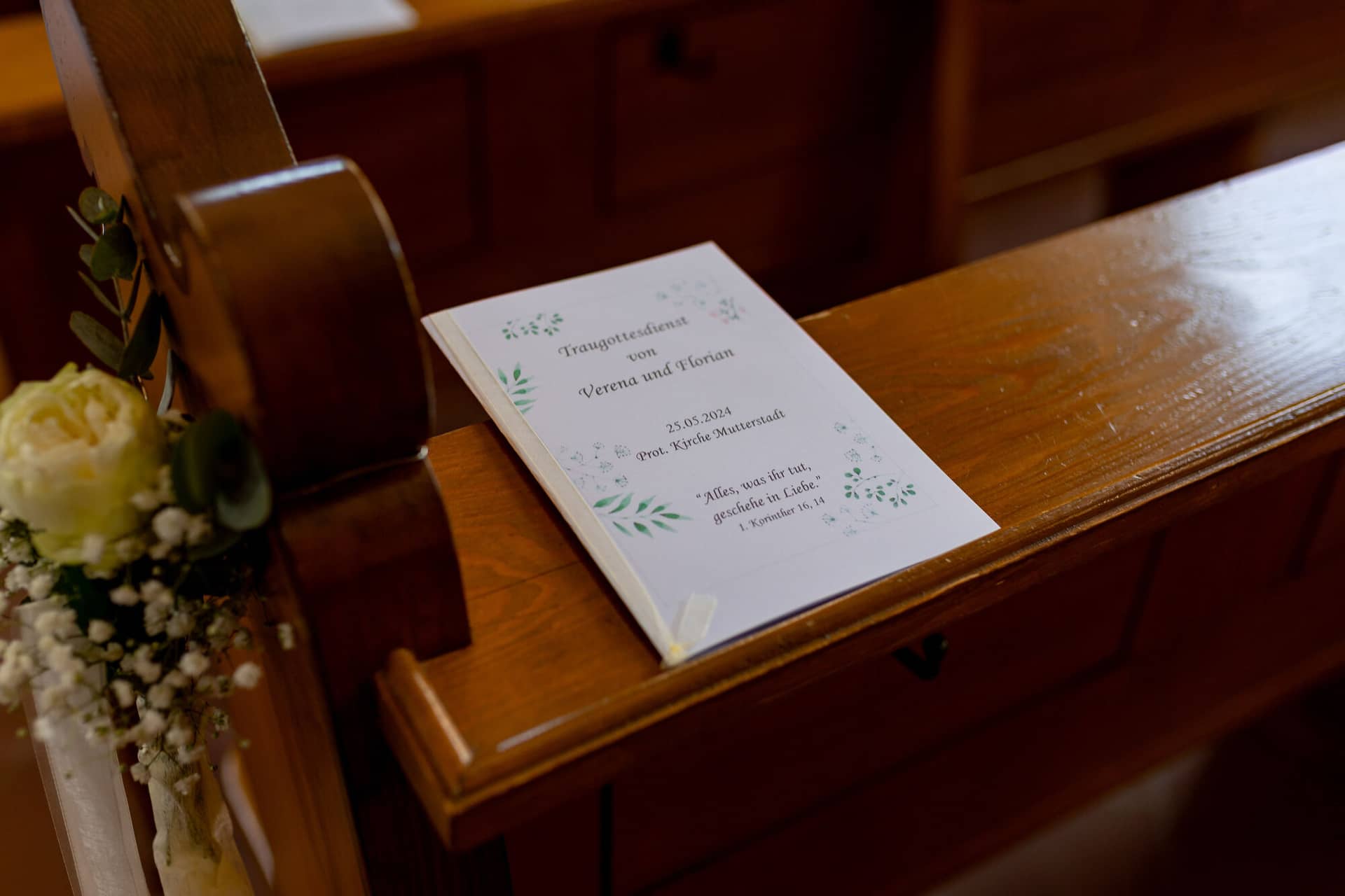 3K8A8298 Hochzeitsfotograf Mutterstadt Grenzhof Heidelberg .DETFAP1h Traureise-Papier mit persönlicher Widmung liegt auf einem Holzbänkchen in der Kirche vor der Trauung