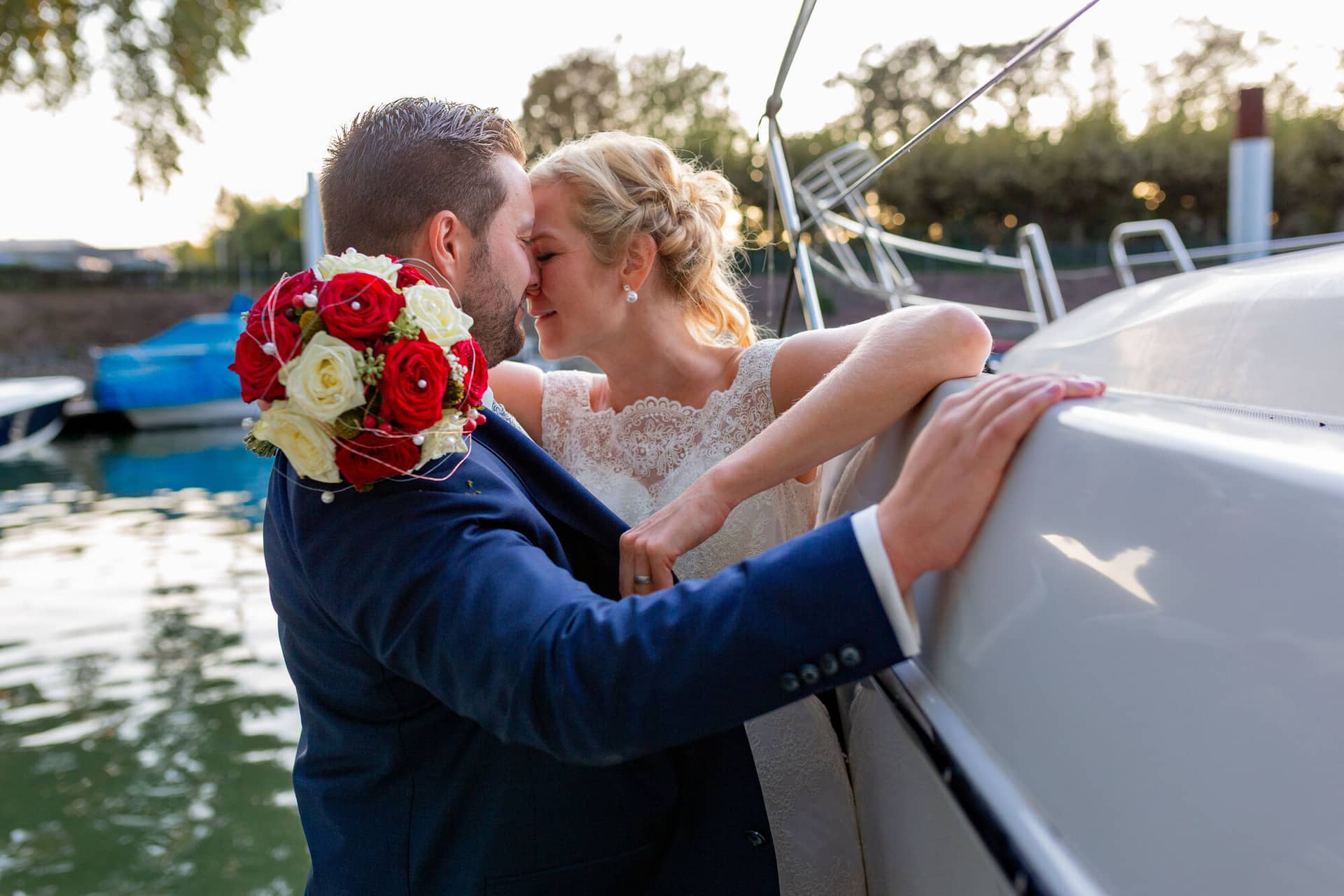 Als Hochzeitsfotograf In Worms 20190921 19 12 59 MK3 2480.Bpai Wsb Brautpaar küsst sich am Yachthafen Worms, rote Blumen im Hintergrund