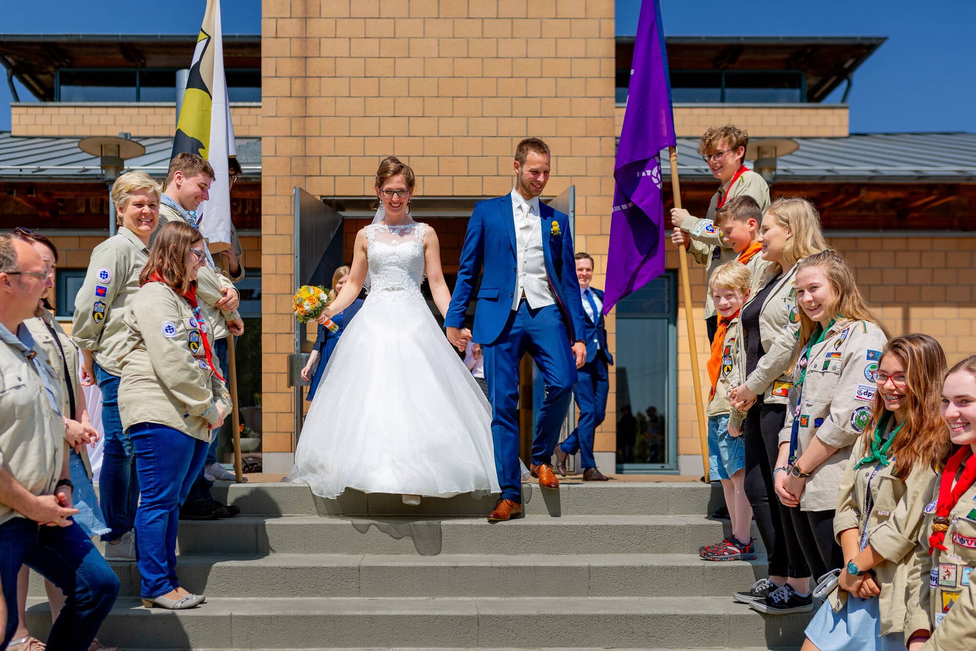 Anne Christian Hochzeitsfotograf Birkenheide Grosskarlbach Bissersheim 00012.DZr8s5 T Bräutigam führt das Brautpaar gemeinsam mit Kindern in Pfadfinder-Shirts auf eine Treppe bei der Zeremonie