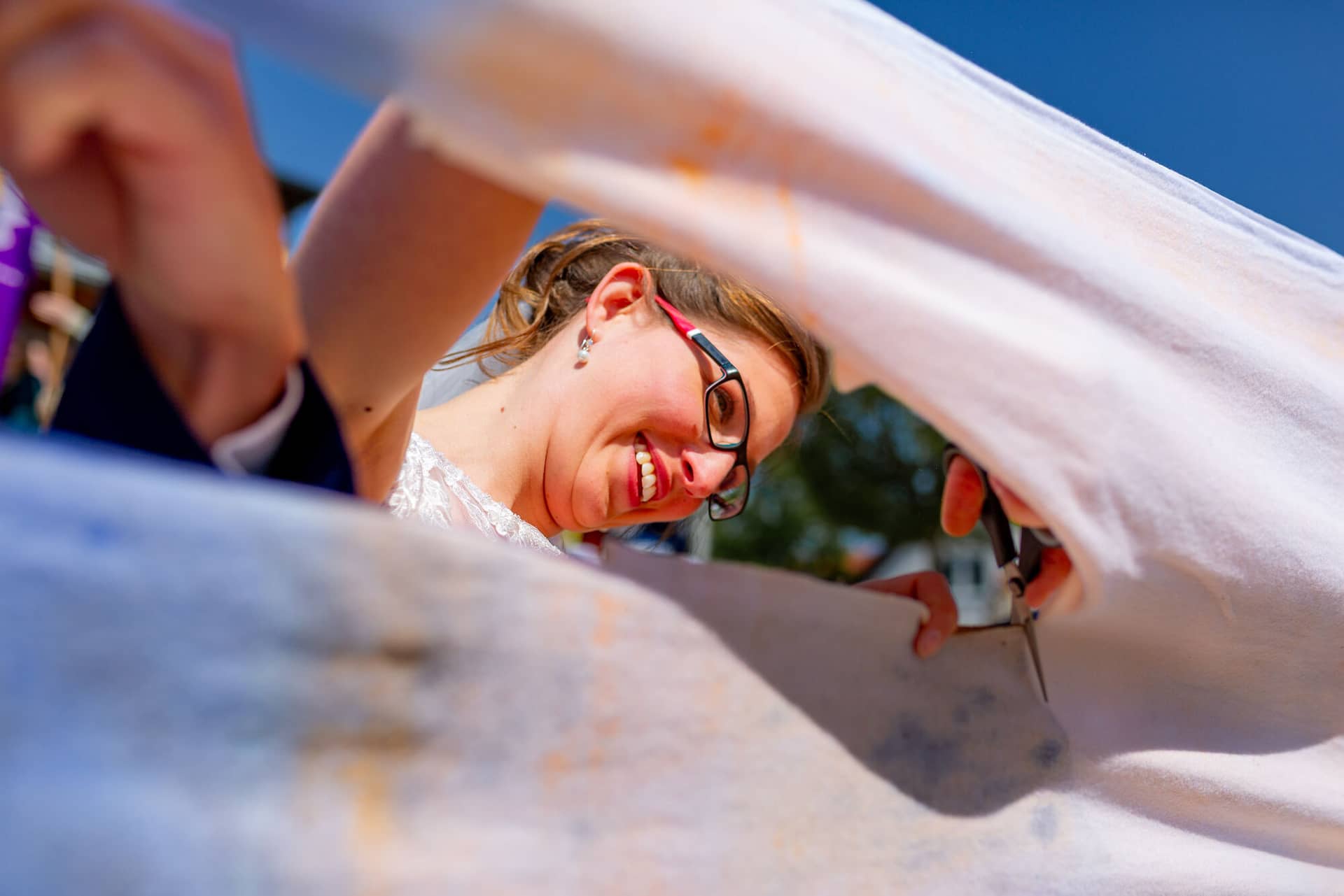 Anne Christian Hochzeitsfotograf Birkenheide Grosskarlbach Bissersheim 00013.Cb4nonzM Braut mit Brille lächelt strahlend beim Einzug unter weißem Tuch in die Freiluft-Zeremonie