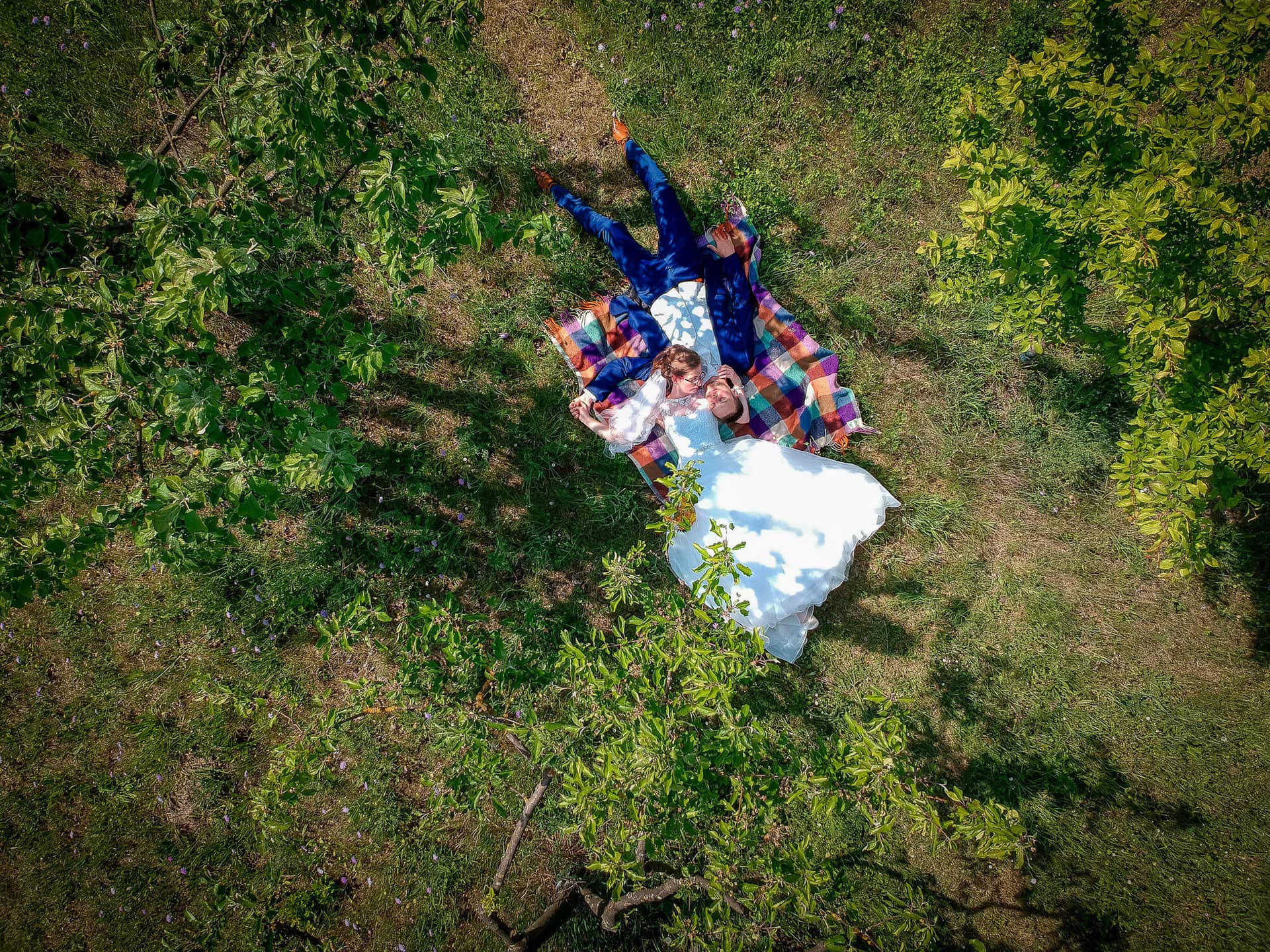 Anne Christian Hochzeitsfotograf Birkenheide Grosskarlbach Bissersheim 00020.DpEMzKvv Hochzeitspaar liegt entspannt auf einer Decke im Grünen, ruht sich unter schattigen Bäumen aus