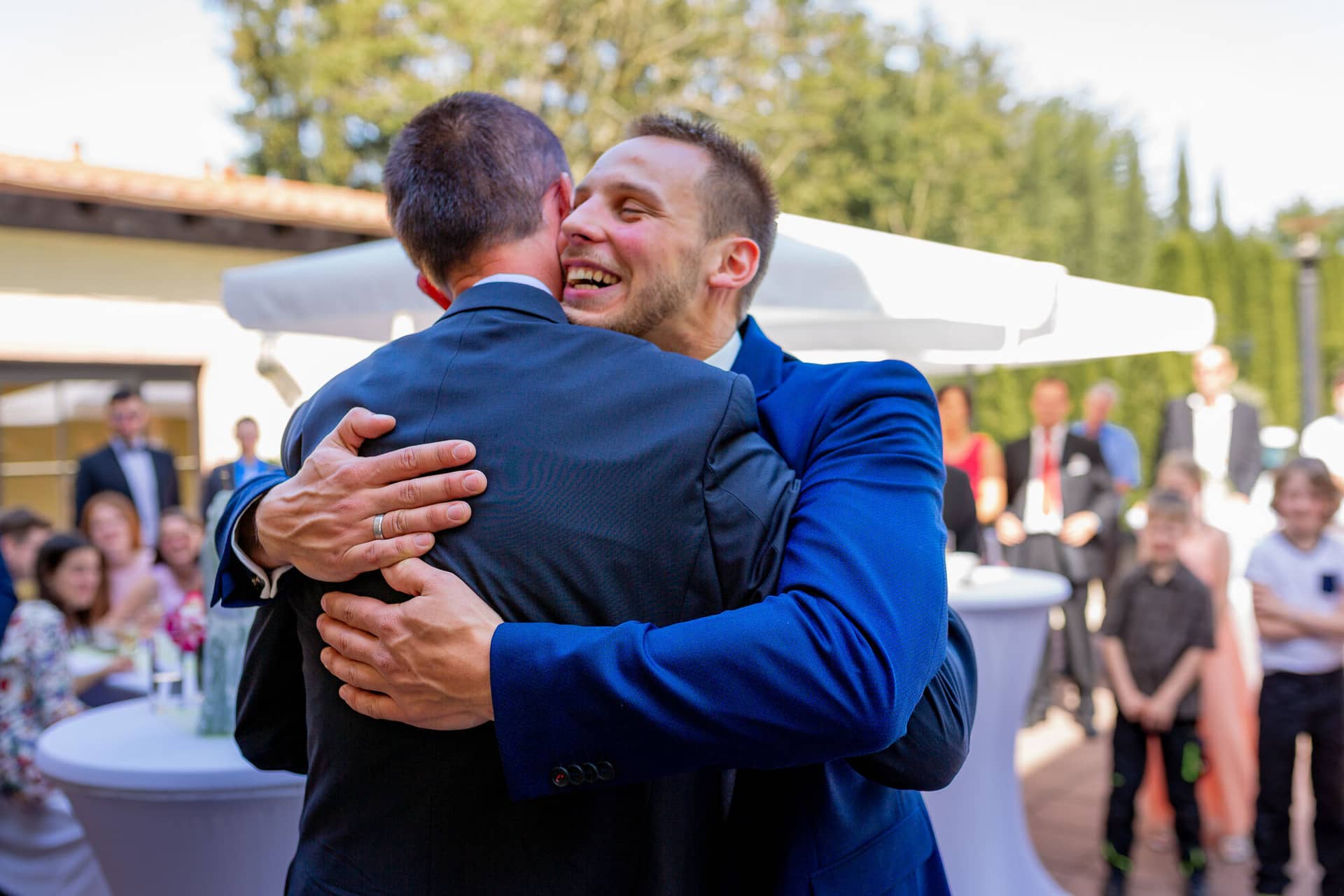 Anne Christian Hochzeitsfotograf Birkenheide Grosskarlbach Bissersheim 00024.DMQl3E86 Zwei junge Männer umarmen sich überglücklich beim Wiedersehen auf dem Hochzeitsgelände