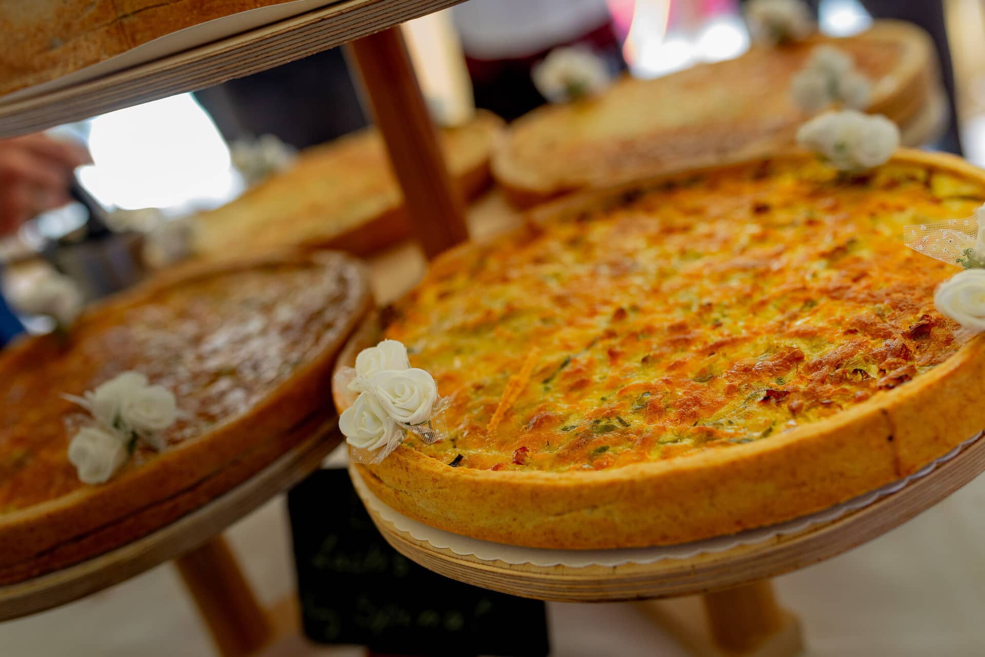 Anne Christian Hochzeitsfotograf Birkenheide Grosskarlbach Bissersheim 00025.ClJ4w5IJ Zwei liebevoll dekorierte Kuchen mit Blumen auf einem Holzgestell, festlicher Hochzeitstisch
