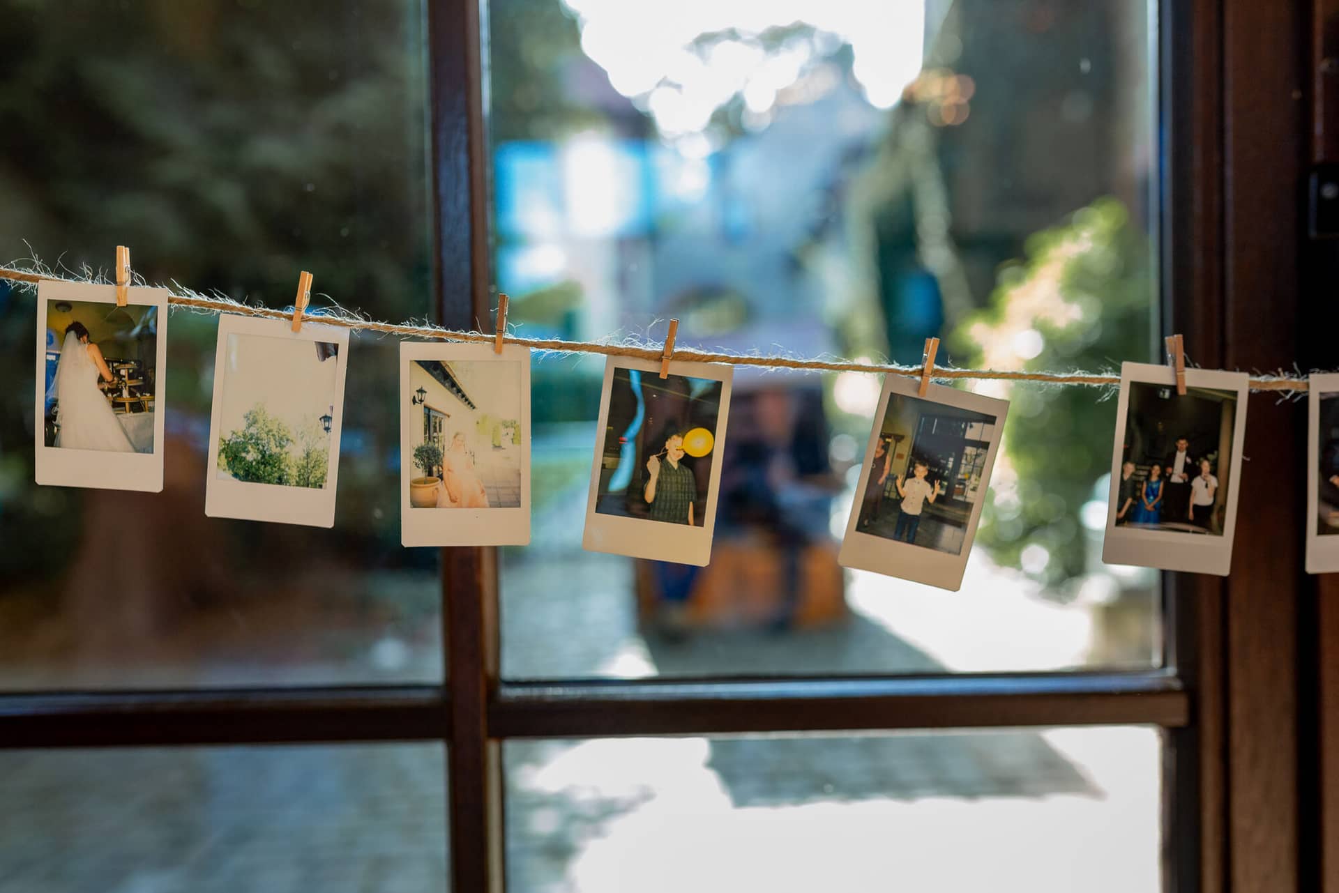 Anne Christian Hochzeitsfotograf Birkenheide Grosskarlbach Bissersheim 00031.DlAFzBWk Aufgehängte Polaroid-Fotos des Brautpaares an einer Leine – persönliche Hochzeitsdekoration im Festsaal