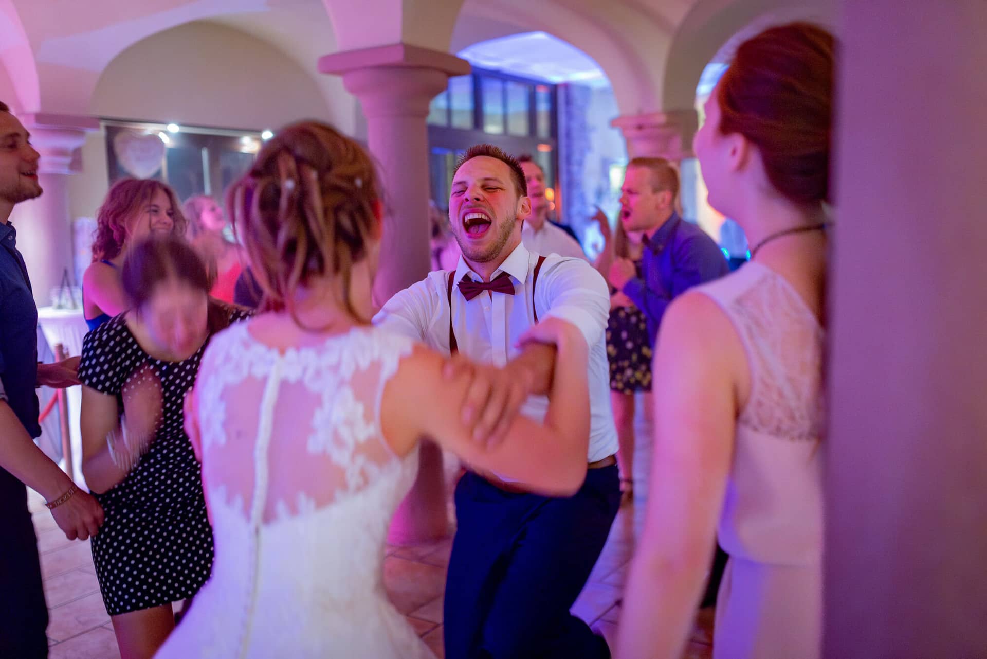 Anne Christian Hochzeitsfotograf Birkenheide Grosskarlbach Bissersheim 00051.1HRecwNI Jubelnder Gast in Weste tanzt mitreißend mit der Braut im Disco-Licht der Hochzeitsparty