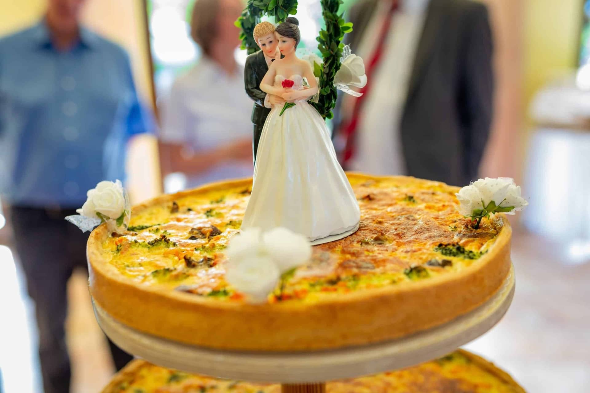 Anne Christian Hochzeitsfotograf Birkenheide Grosskarlbach Bissersheim 13.DqaXH61A Hochzeitsfigur auf einem Geldbrot mit weißen Blüten – Kuchendeko-Detail bei der Hochzeitsfeier