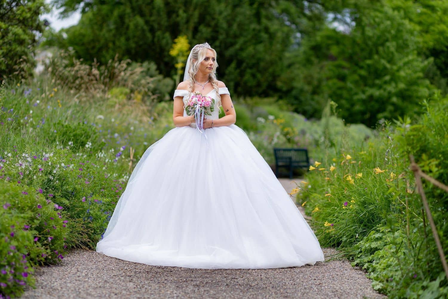 Brautpaarshooting Weinheim Schlossgarten Heidelberg Freie Trauung 4K8A5121 5700dbb0 1500.CIHlXDY Braut in weißem Ballkleid mit Schleier steht allein auf gepflastertem Gartenweg im Hermannshof Weinheim