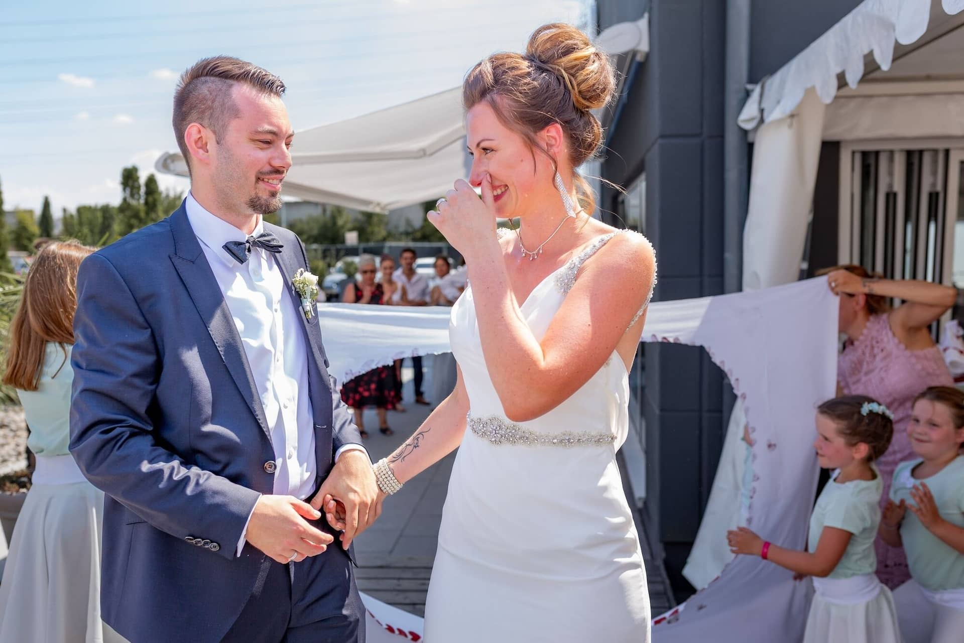 Hochzeit Schwetzingen Hochzeitsfotograf Heiraten Miio MK3 8081.6Eu3xjuk Bräutigam lächelt seiner gerührten Braut liebevoll an, Blumenmädchen und Gäste im Hintergrund