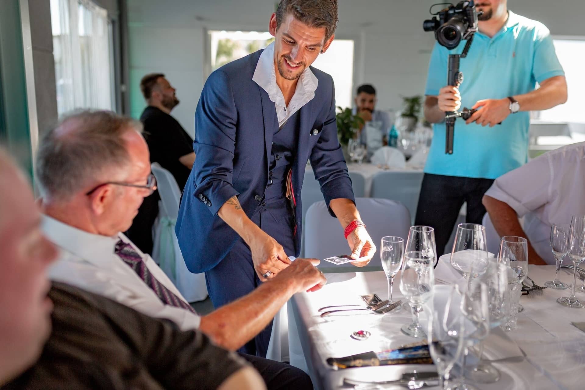 Hochzeit Schwetzingen Hochzeitsfotograf Heiraten Miio MK3 8415.CsXBy7mU Gäste beim festlichen Empfang, Mann verteilt Tischkarten an den dekorierten Hochzeitstischen