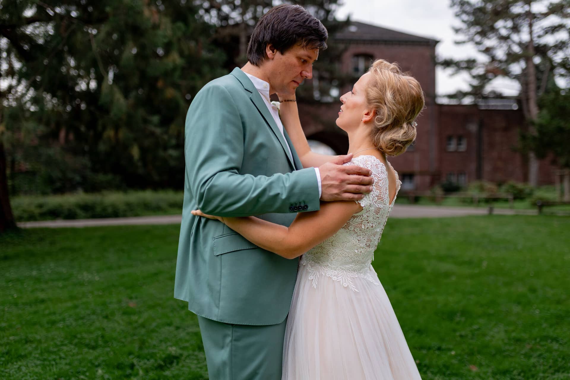 Hochzeitsfotograf Karlsruhe Daniela Matthias 20230819 14 31 36 4K8A5956.GvBP3E J Bräutigam hält die Hände der strahlenden Braut im Spitzenkleid, historisches Schlossgebäude im Hintergrund