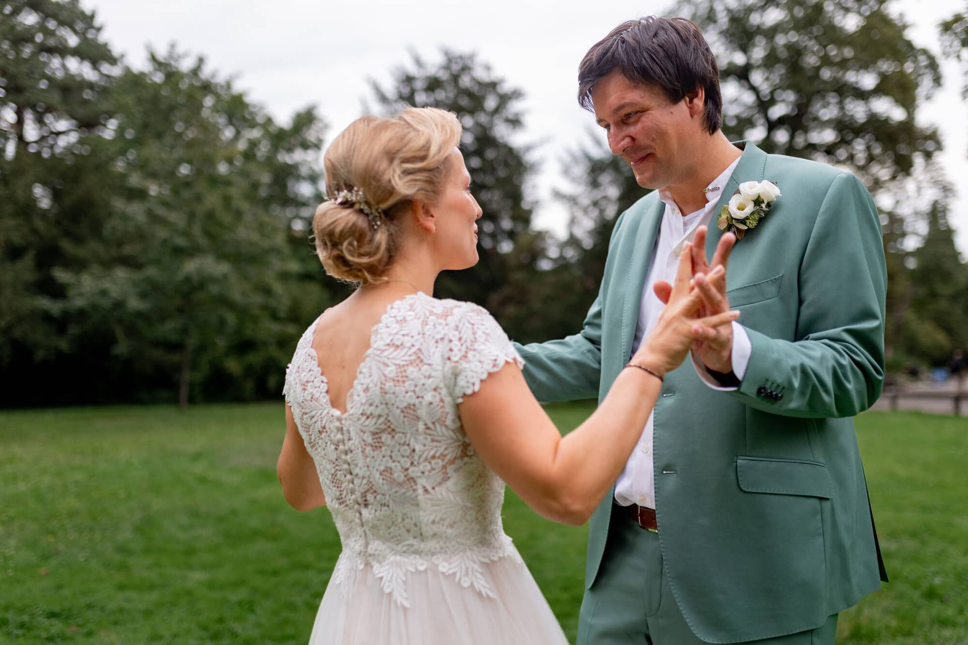 Hochzeitsfotograf Karlsruhe Daniela Matthias 20230819 14 31 51 4K8A6006.5Ed0HYZF Brautpaar tanzt ausgelassen auf grüner Wiese im Schlossgarten, umgeben von alten Bäumen