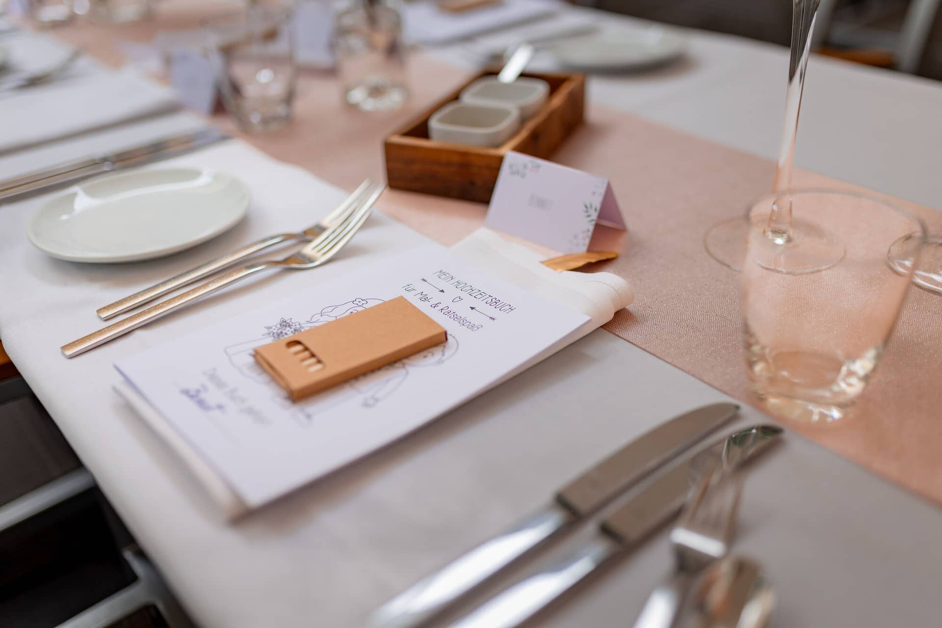 Hochzeitsfotograf Karlsruhe Daniela Matthias 20230819 15 09 07 4K8A6585.CnmCiAeL Gedeckter Hochzeitstisch mit Menükarte, Holzkasten und rosafarbenen Servietten, liebevoll arrangierte Tischdekoration