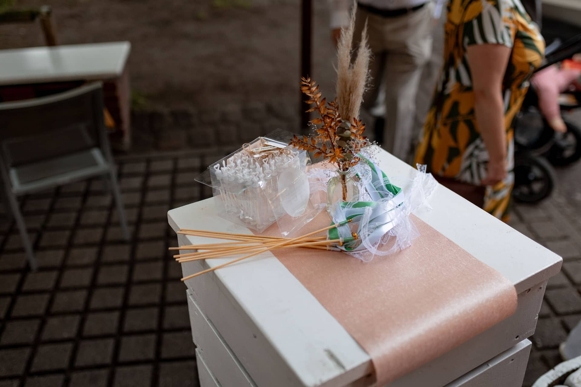 Hochzeitsfotograf Karlsruhe Daniela Matthias 20230819 15 10 07 4K8A6591.CMTH3C84 Ringkasten mit goldenen Eheringen auf rosafarbenem Tuch, dekoriert mit getrockneten Blüten auf Pflasterweg