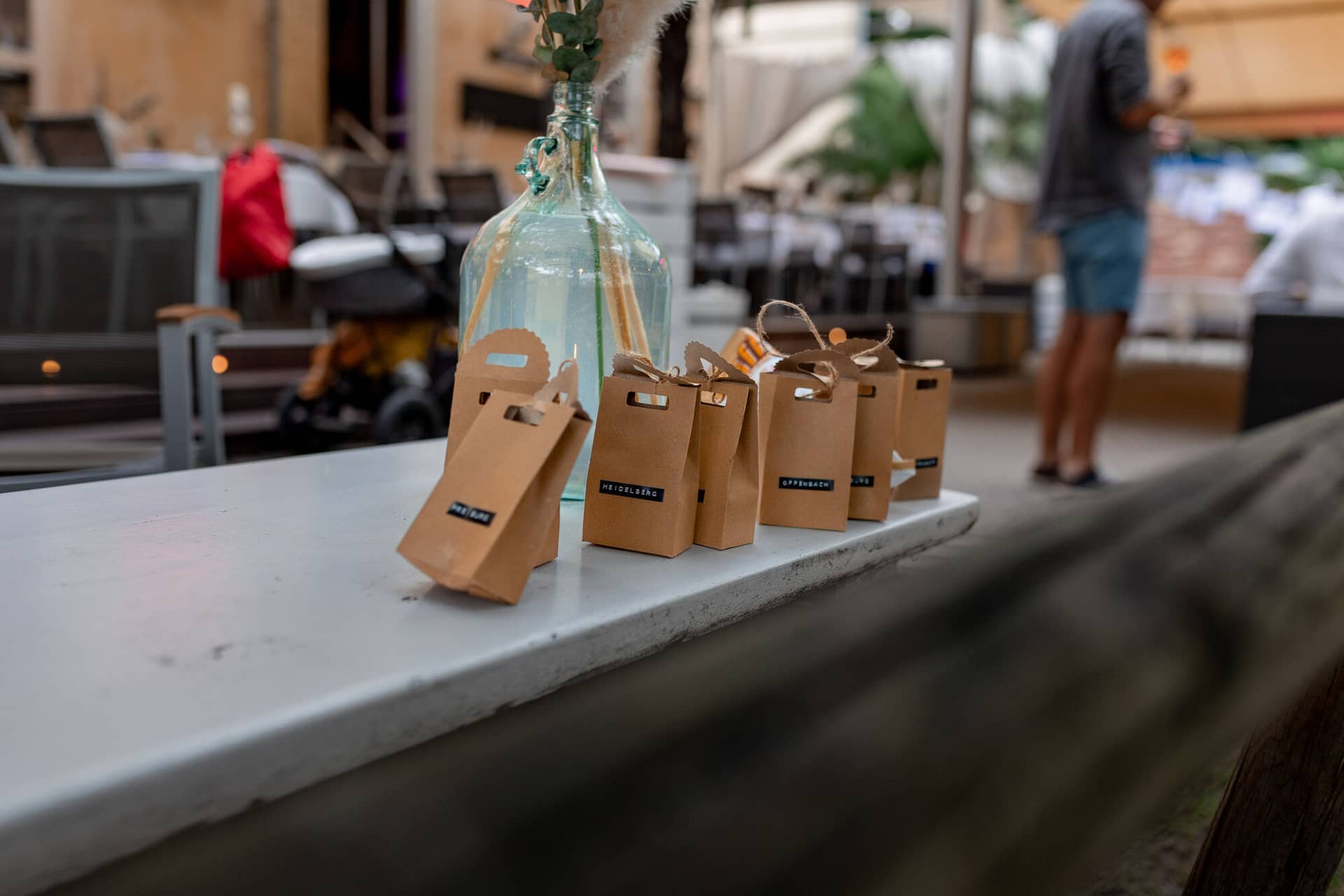 Hochzeitsfotograf Karlsruhe Daniela Matthias 20230819 15 55 19 4K8A8720.DhlBzz4Q Papiertüten mit „Heidelberg"-Aufdruck als persönliche Gastgeschenke auf dem Tisch der Hochzeitsfeier