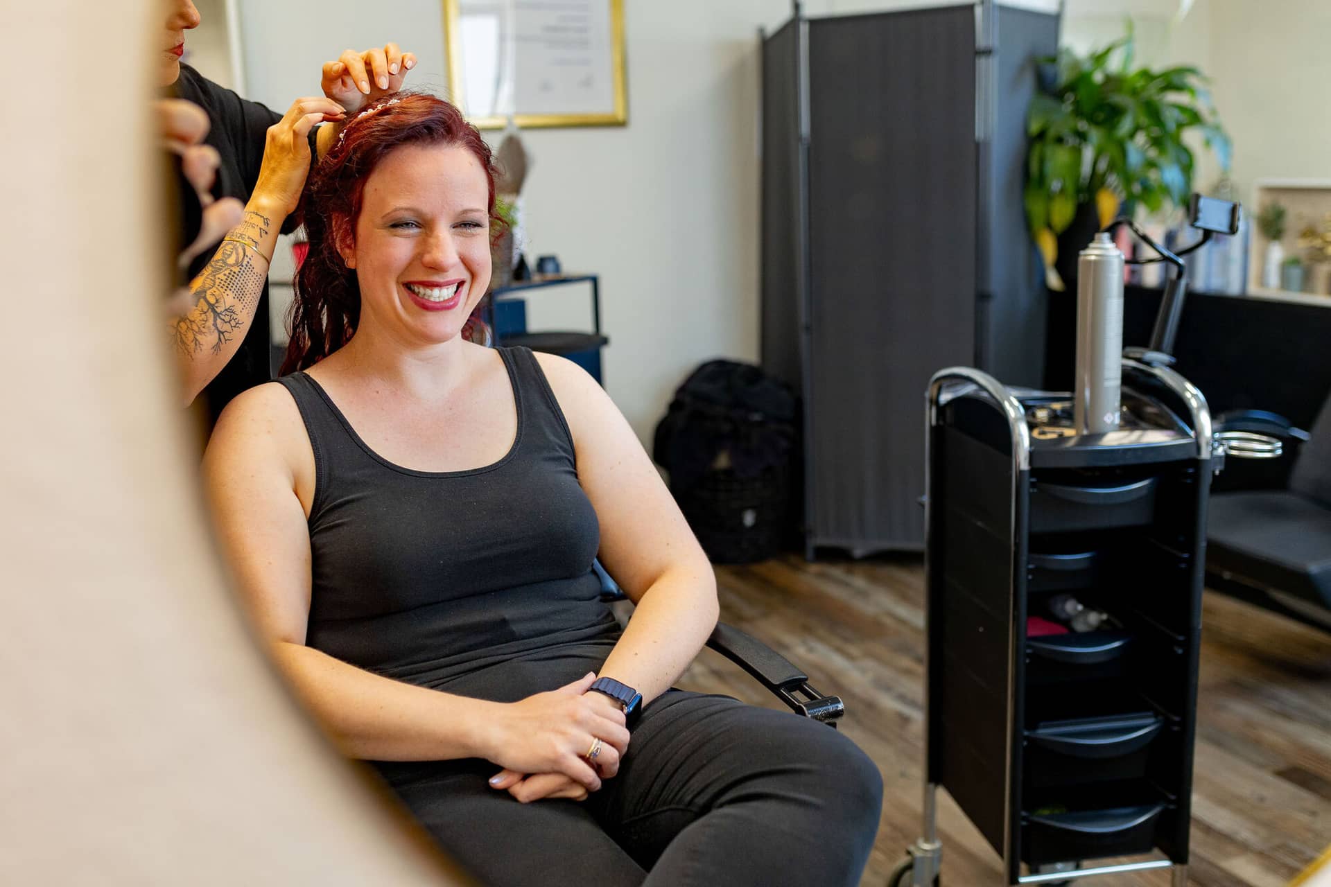 Hochzeitsfotograf Neustadt Hambacher Schloss Ruppertsberg Kellers Keller 03.B4SU6 6T Strahlende Braut lächelt während Friseurin Hochzeitsfrisur stylt