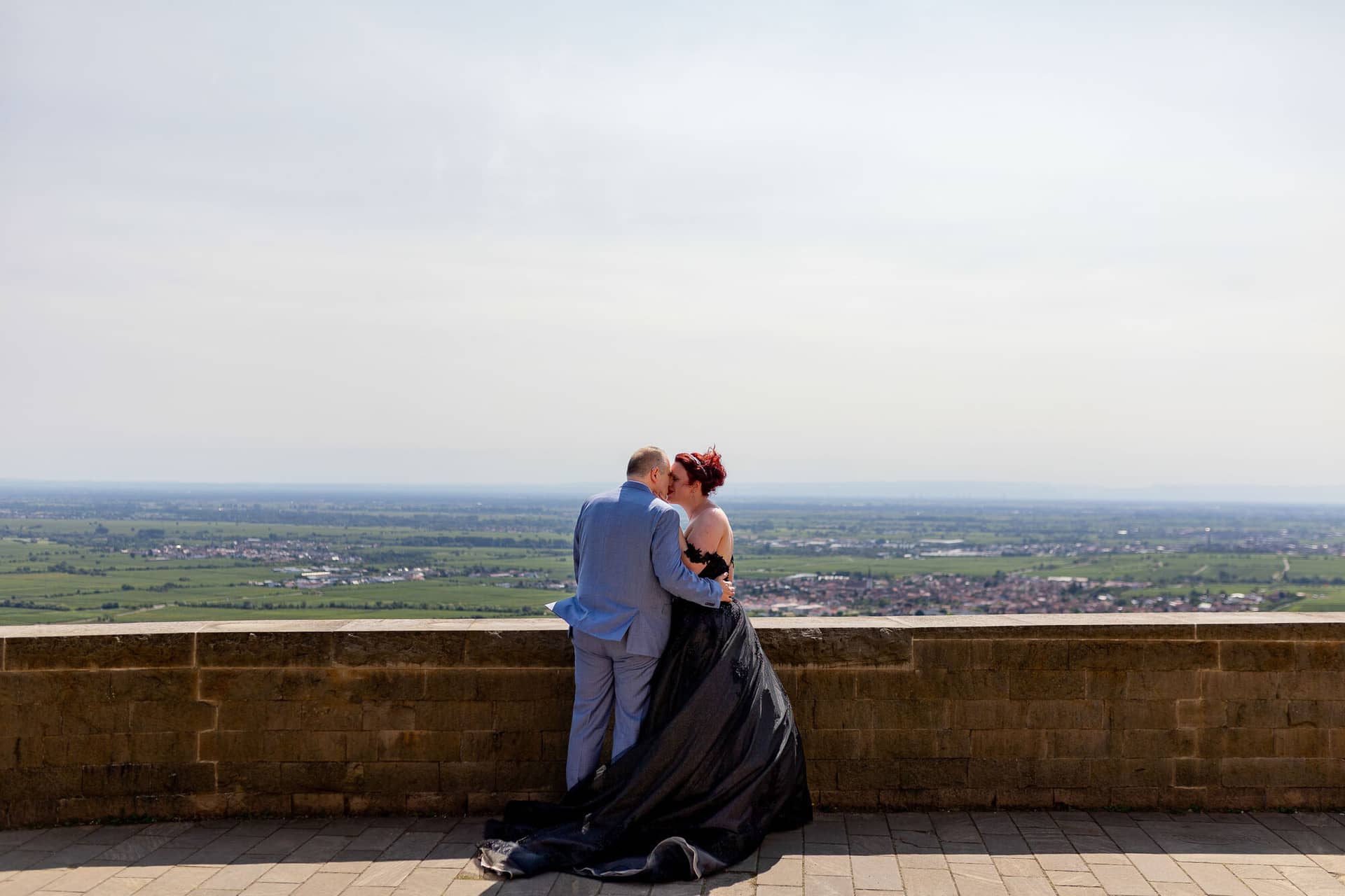 Hochzeitsfotograf Neustadt Hambacher Schloss Ruppertsberg Kellers Keller 11.5R10IAPj Brautpaar küsst sich auf Schlossterrasse mit weitem Panoramablick über die pfälzische Rheinebene