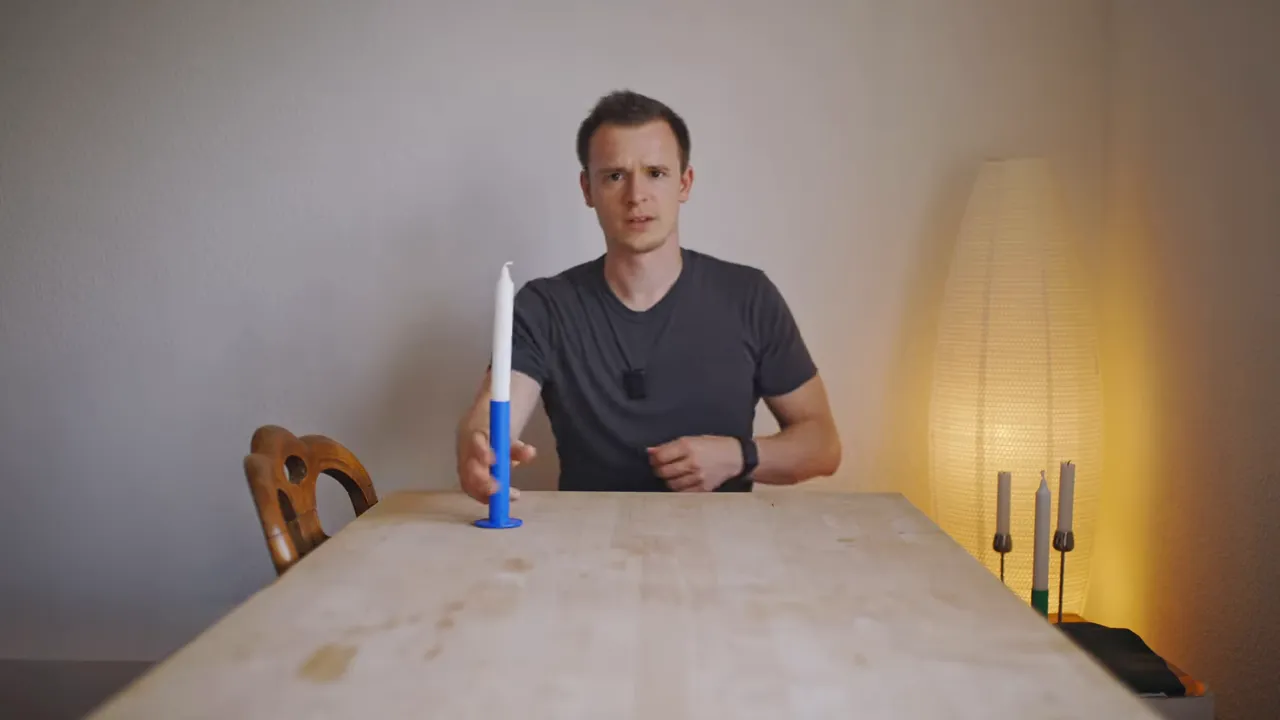 Person am Tisch zeigt blauen Kerzenhalter vor warmem Lampenlicht