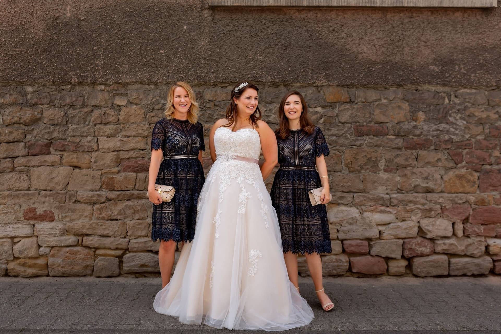 Standesamtliche Trauung Mutterstadt Altes Rathaus Bad Duerkheim Schlossgarten IMG 2457.CxsH 6Kq Braut mit zwei Brautjungfern lächelt vor historischem Steingebäude im Ortskern Mutterstadt