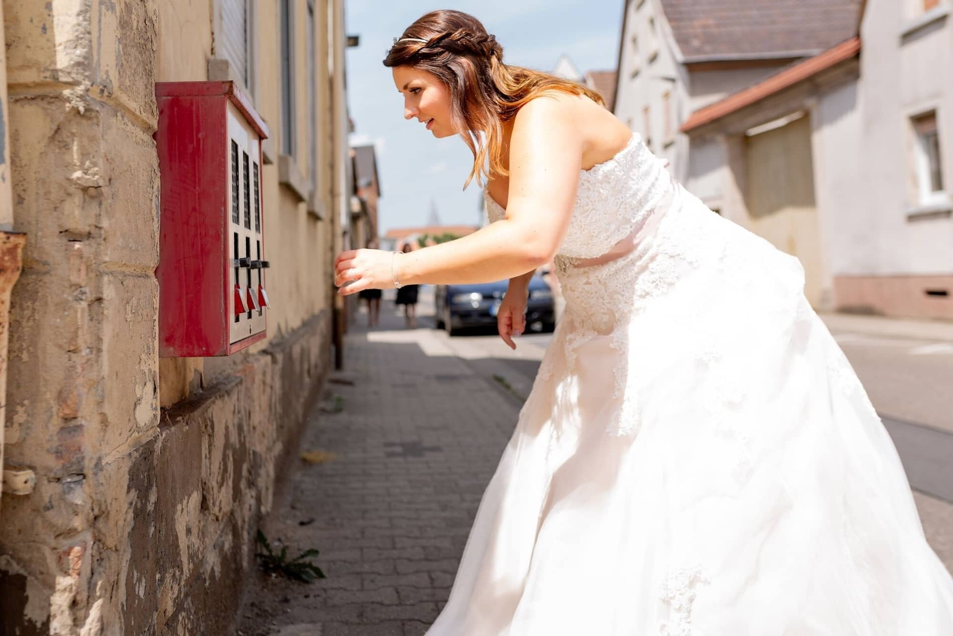 Standesamtliche Trauung Mutterstadt Altes Rathaus Bad Duerkheim Schlossgarten IMG 2486.K2ZZ4pgf Braut im weißen Kleid streift spielerisch über roten Postkasten in der Gasse von Mutterstadt