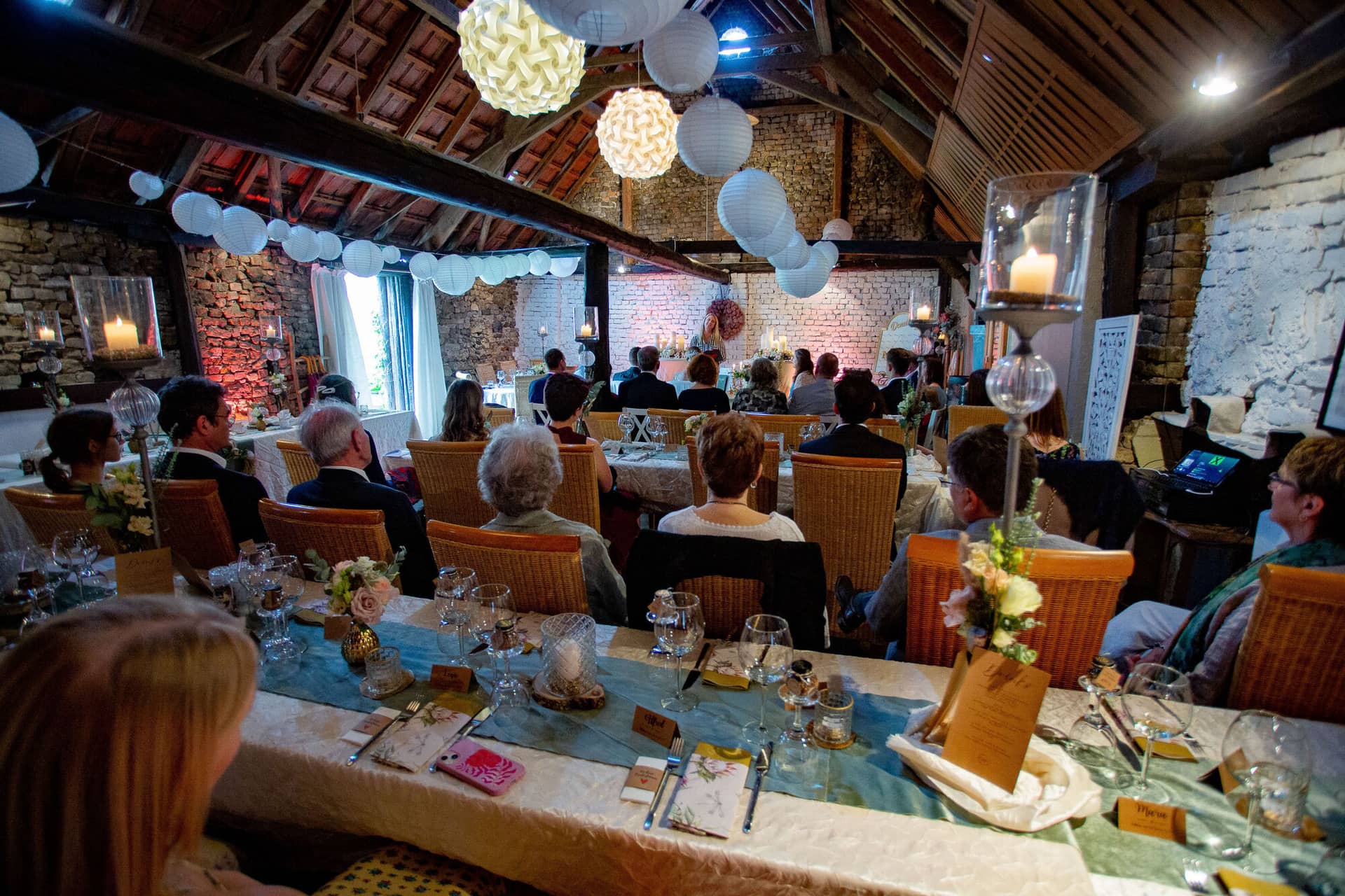 Verena Marius Hochzeitsfotograf Fotograf Worms Mettenheim 20.CbPKy98o Stimmungsvolles Hochzeitsdinner im strohgedeckten Festsaal mit Papierlaternen und Kerzenlicht, viele Gäste am langen Tisch