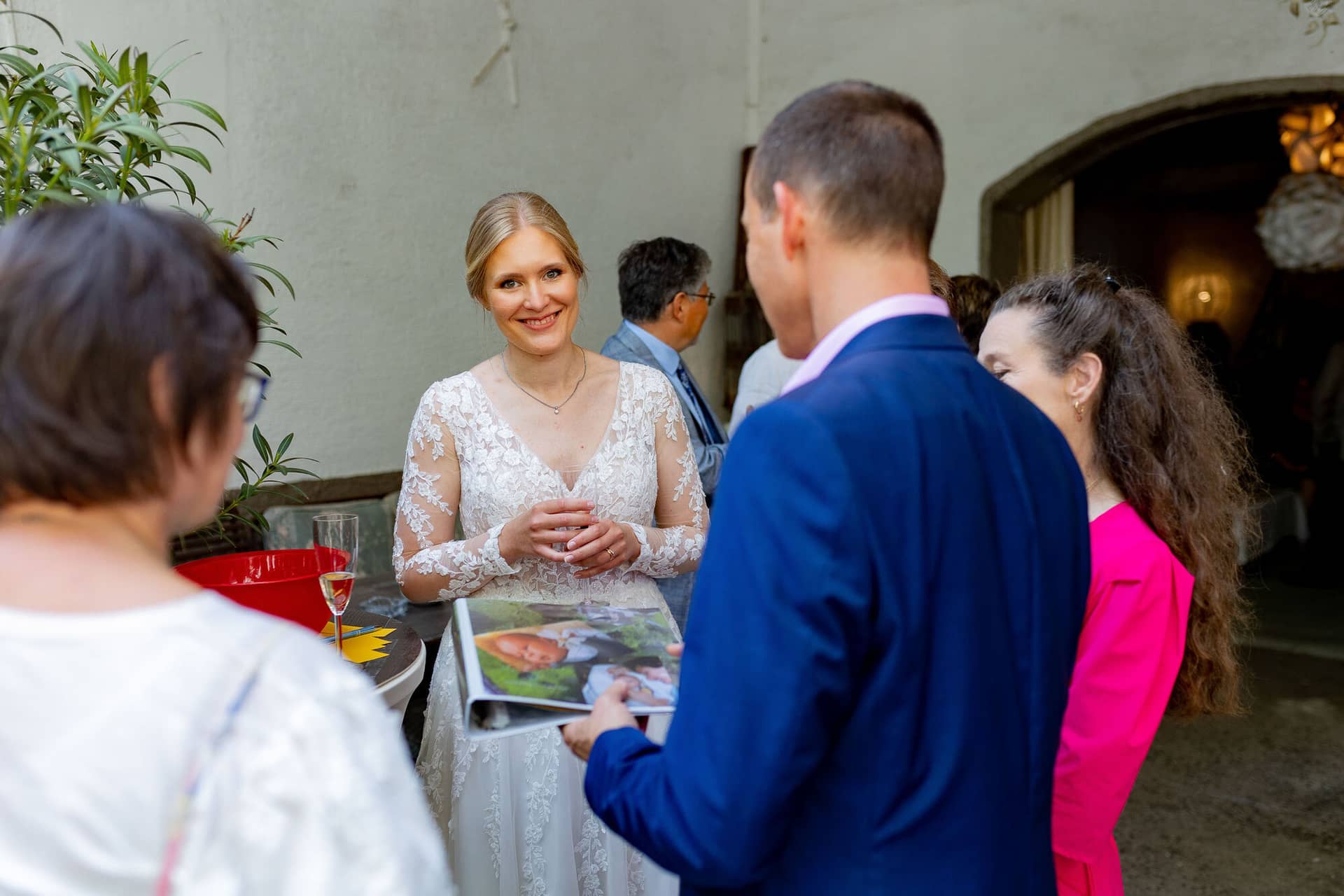 Verena Marius Hochzeitsfotograf Fotograf Worms Mettenheim 23.BhvpiUqk Braut im weißen Spitzenkleid bei abendlichem Gespräch mit Bräutigam und Gästen im Garten der Location