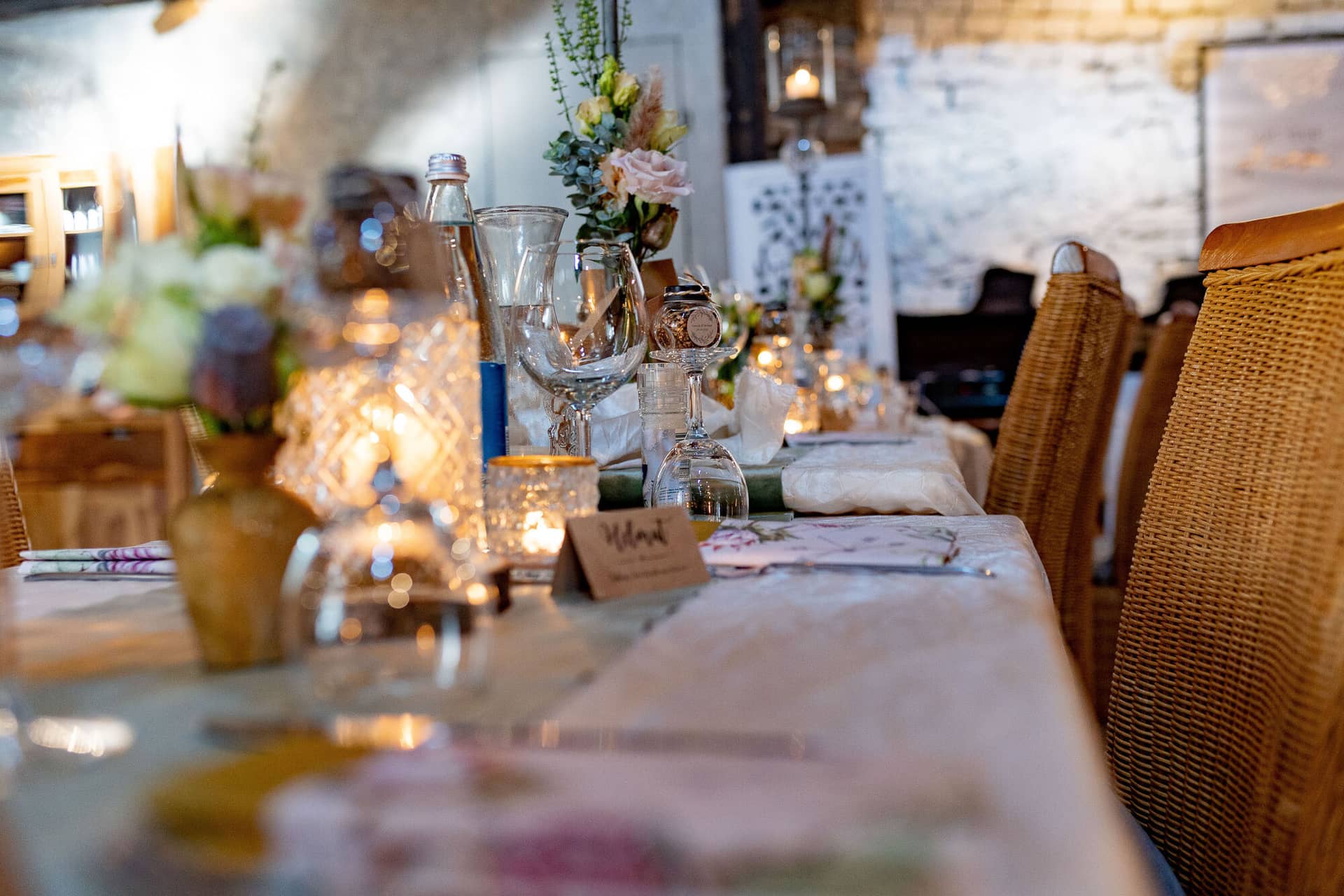 Verena Marius Hochzeitsfotograf Fotograf Worms Mettenheim 24.BDagvcVd Langer Festtisch mit Blumenarrangements, Champagnergläsern und Kerzenlicht vor der rustikalen Ziegelwand