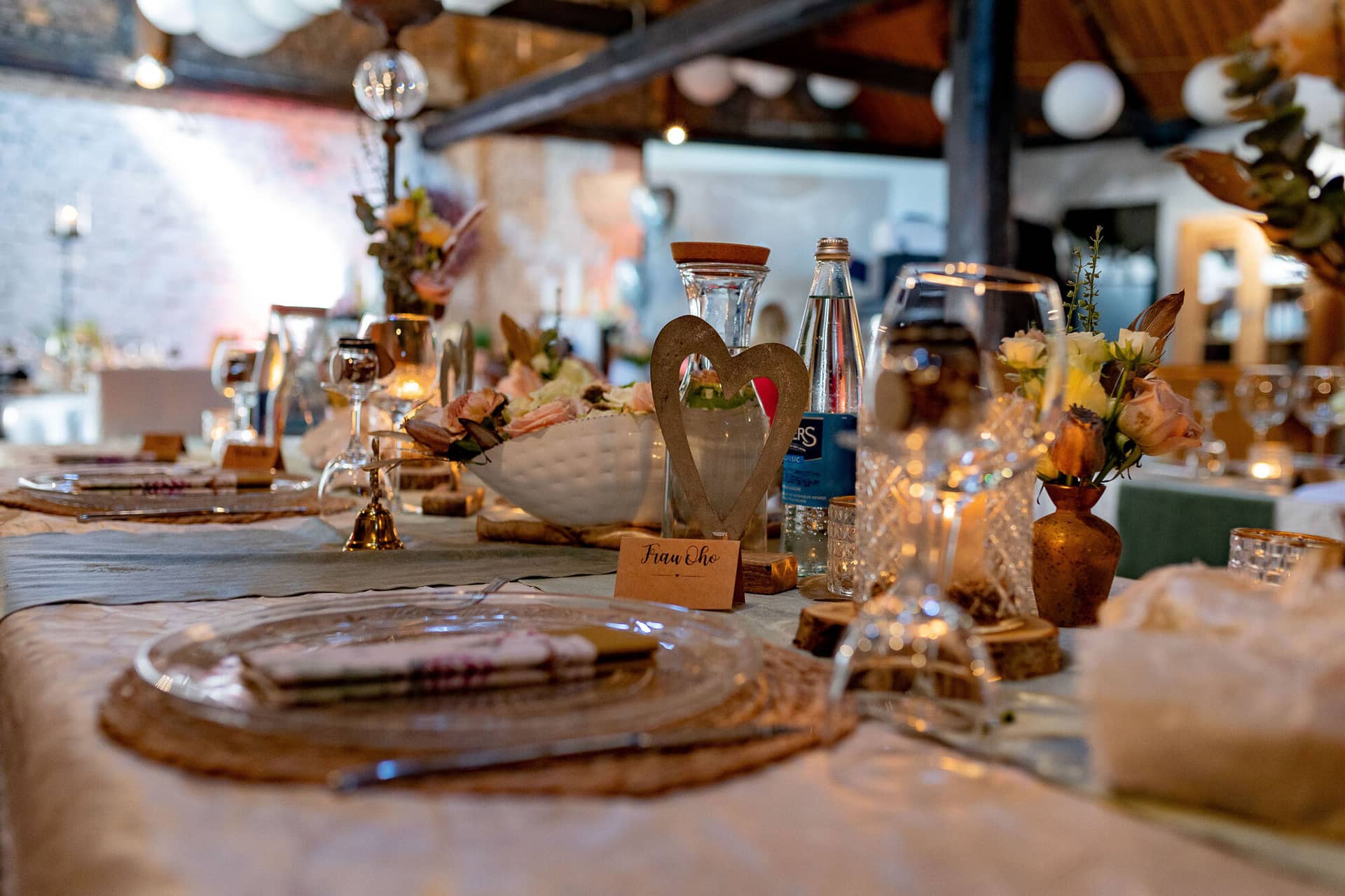 Verena Marius Hochzeitsfotograf Fotograf Worms Mettenheim 25.CIDHV7fZ Gedeckter Tisch mit Blumendekoration in rustikal-charmantem Saal mit Ziegelwänden und Holzbalkendecke
